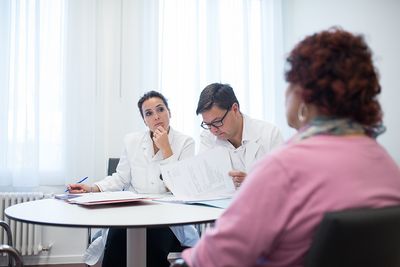 Zwei Ärzte hören einer Patientin aufmerksam zu