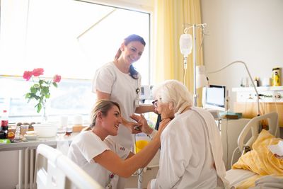 Zwei Pflegerinnen besuchen eine betagte Patientin