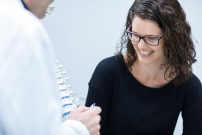 Eine Frau sieht sich lächelnd die Erklärungen des Spezialisten an.