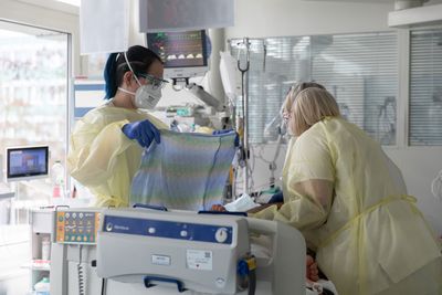 Zwei Pflegerinnen kümmern sich um einen Patienten